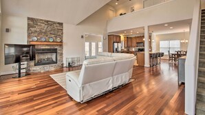 A spacious living room with a stone fireplace, a large white sofa, and a wooden floor. - Dreamy Ridgeway Home w/ Grill on Lake Wateree! (Winnsboro)