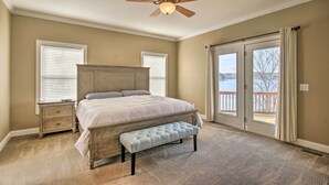 A bedroom with a large bed, a bench, a nightstand, and a ceiling fan. - Dreamy Ridgeway Home w/ Grill on Lake Wateree! (Winnsboro)
