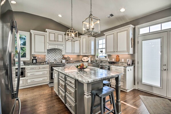 A spacious kitchen with white cabinetry, a large island with stools, and pendant lighting.