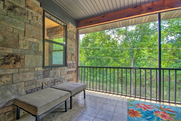 A balcony with stone walls, a bench, and a view of trees.
