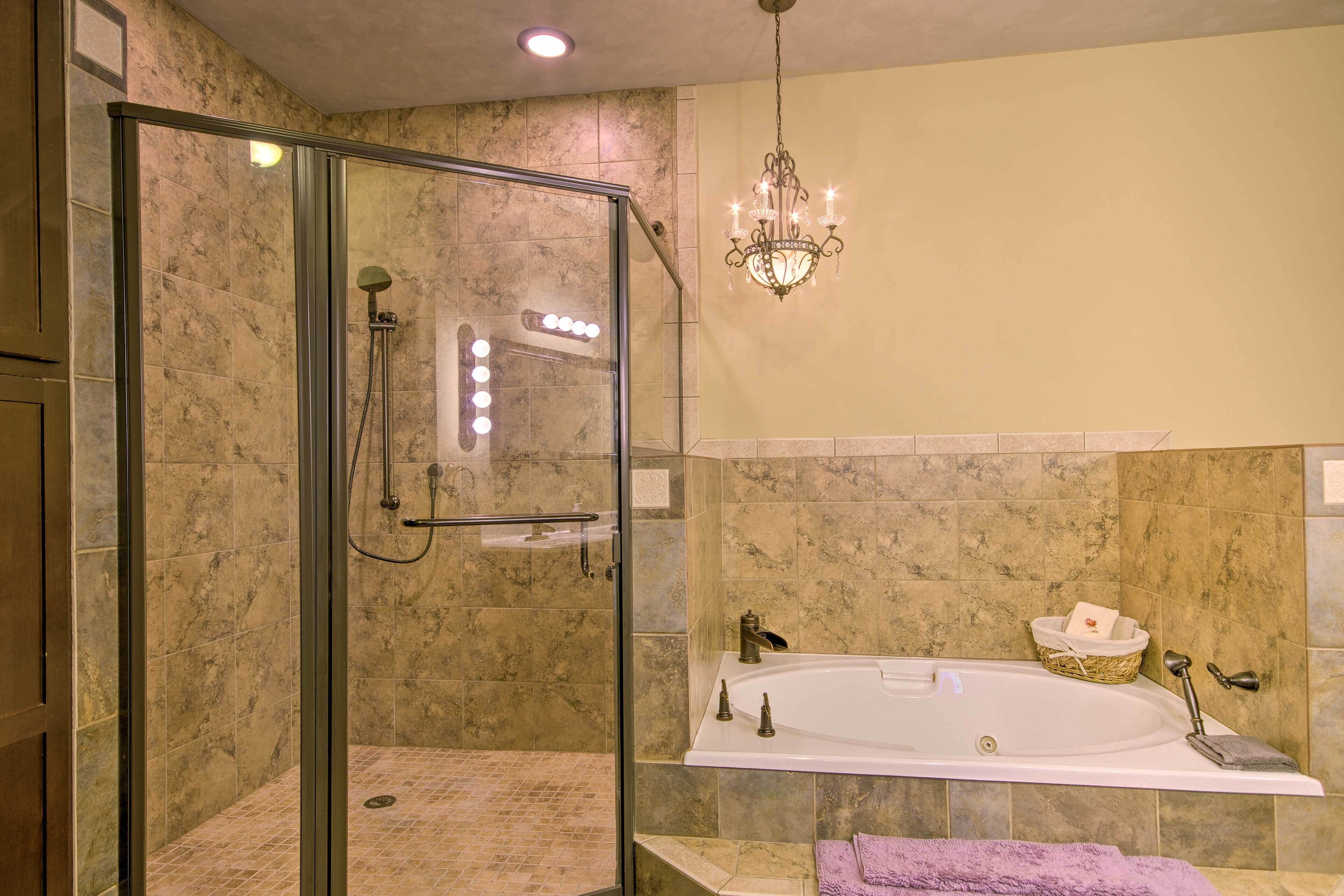 Un baño moderno con ducha envuelta en vidrio, una bañera independiente y un candelabro.