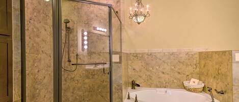 Un baño moderno con ducha envuelta en vidrio, una bañera independiente y un candelabro.