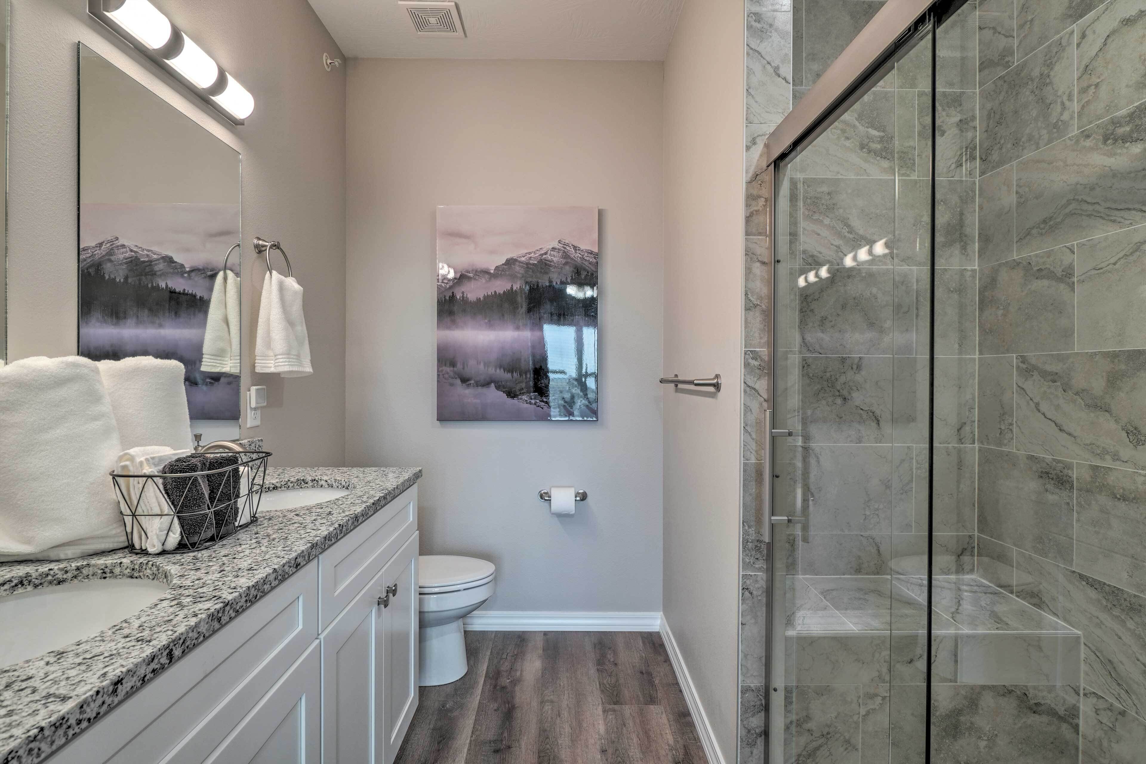 A bathroom with a shower, a toilet, a sink, and a large mirror.