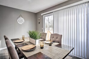 A dining area with a dark wooden table, beige placemats, and a potted plant.