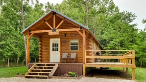 A wooden cabin named "The Big Rock" with a porch, two chairs, and a small deck.