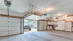 A garage with a car, a workbench, cabinets, and a ceiling-mounted projector. - Lakefront Family Retreat in Osage Beach! (Osage Beach)