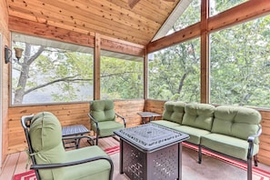 A wooden deck with a green sofa, two chairs, and a small table.
