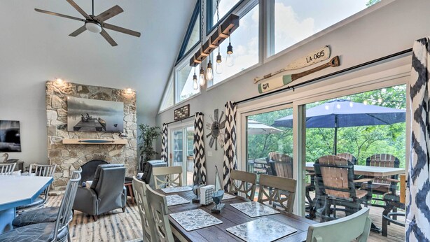 An indoor dining area with a stone wall, a ceiling fan, and a view of the outdoors. - Lakefront Family Retreat in Osage Beach! (Osage Beach)