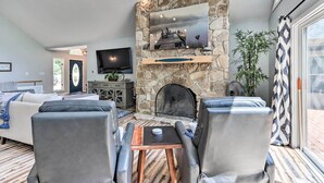 A living room with a stone fireplace, leather chairs, a TV, and a large window. - Lakefront Family Retreat in Osage Beach! (Osage Beach)