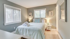 Ein Schlafzimmer mit einem Bett, zwei Nachttischen, zwei Fensterläden und zwei Jalousien.