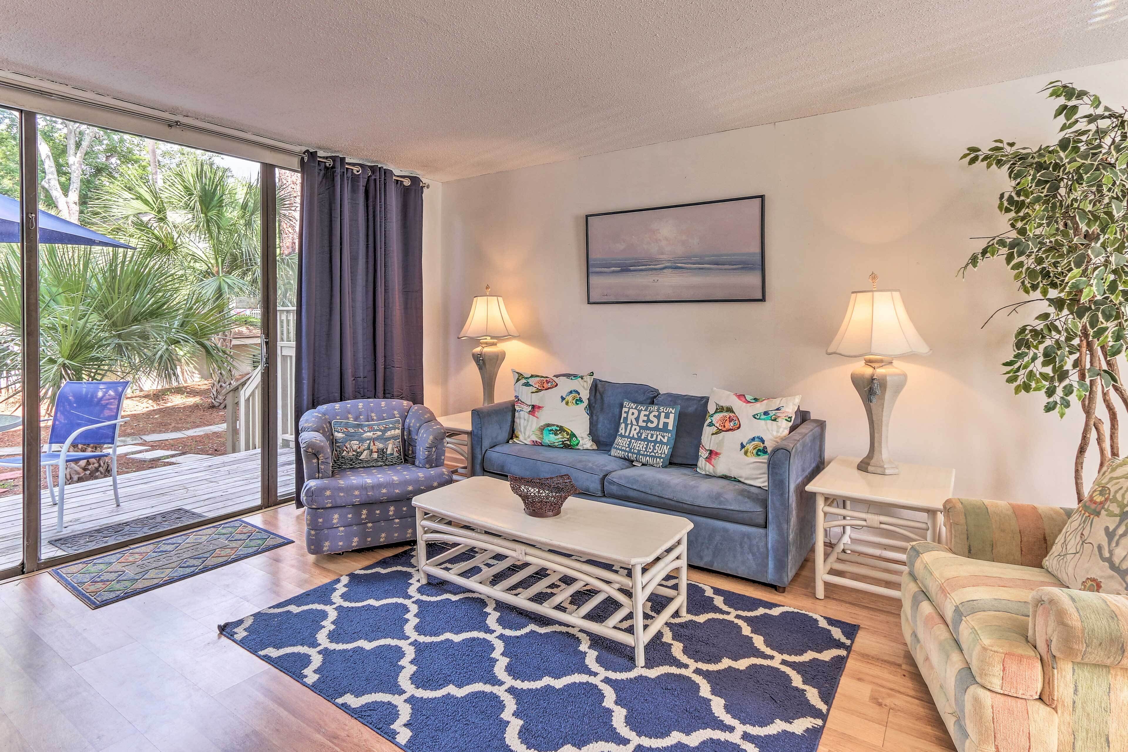 A living room with a sofa, armchairs, a coffee table, and a view of the outdoors.