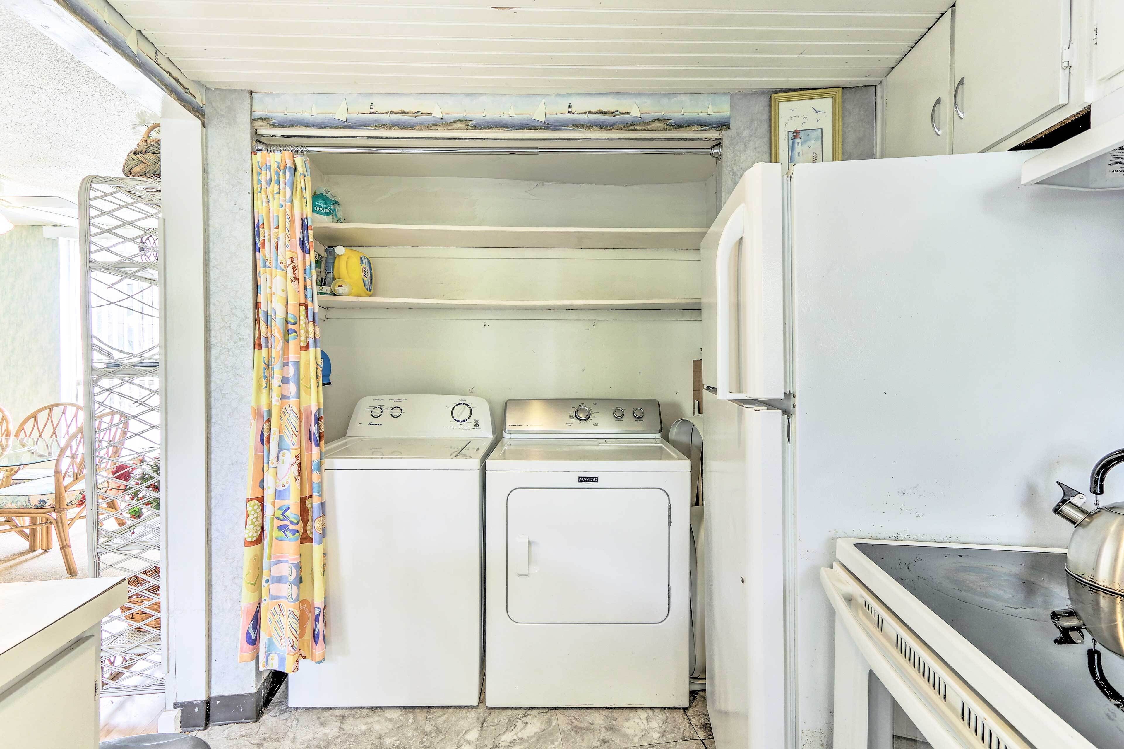 A compact laundry room with two washing machines, a dryer, and a small sink.