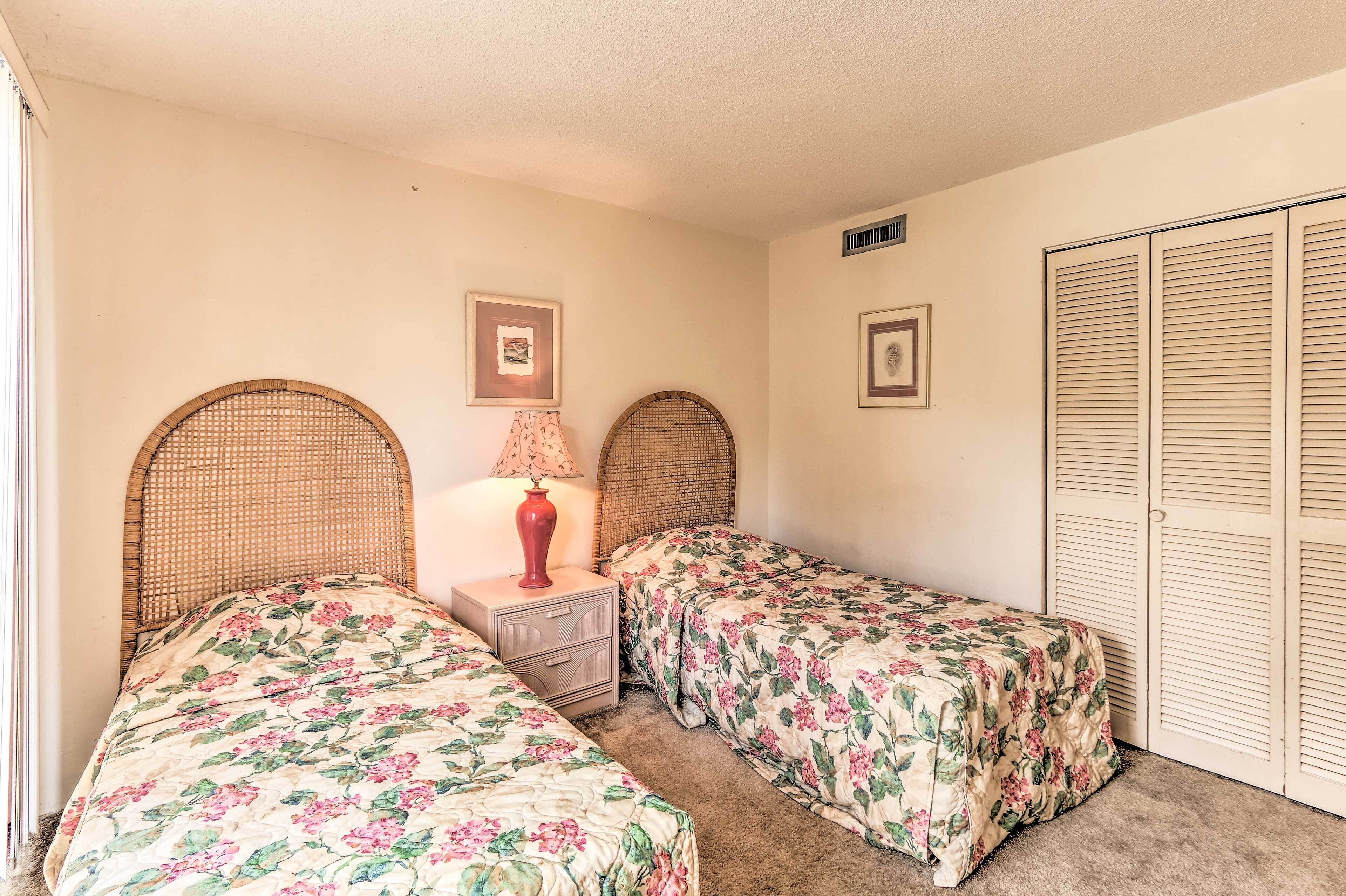A bedroom with two single beds, a nightstand with a lamp, and a wardrobe.