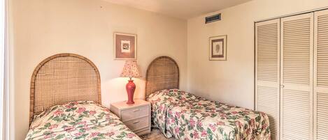 A bedroom with two single beds, a nightstand with a lamp, and a wardrobe.