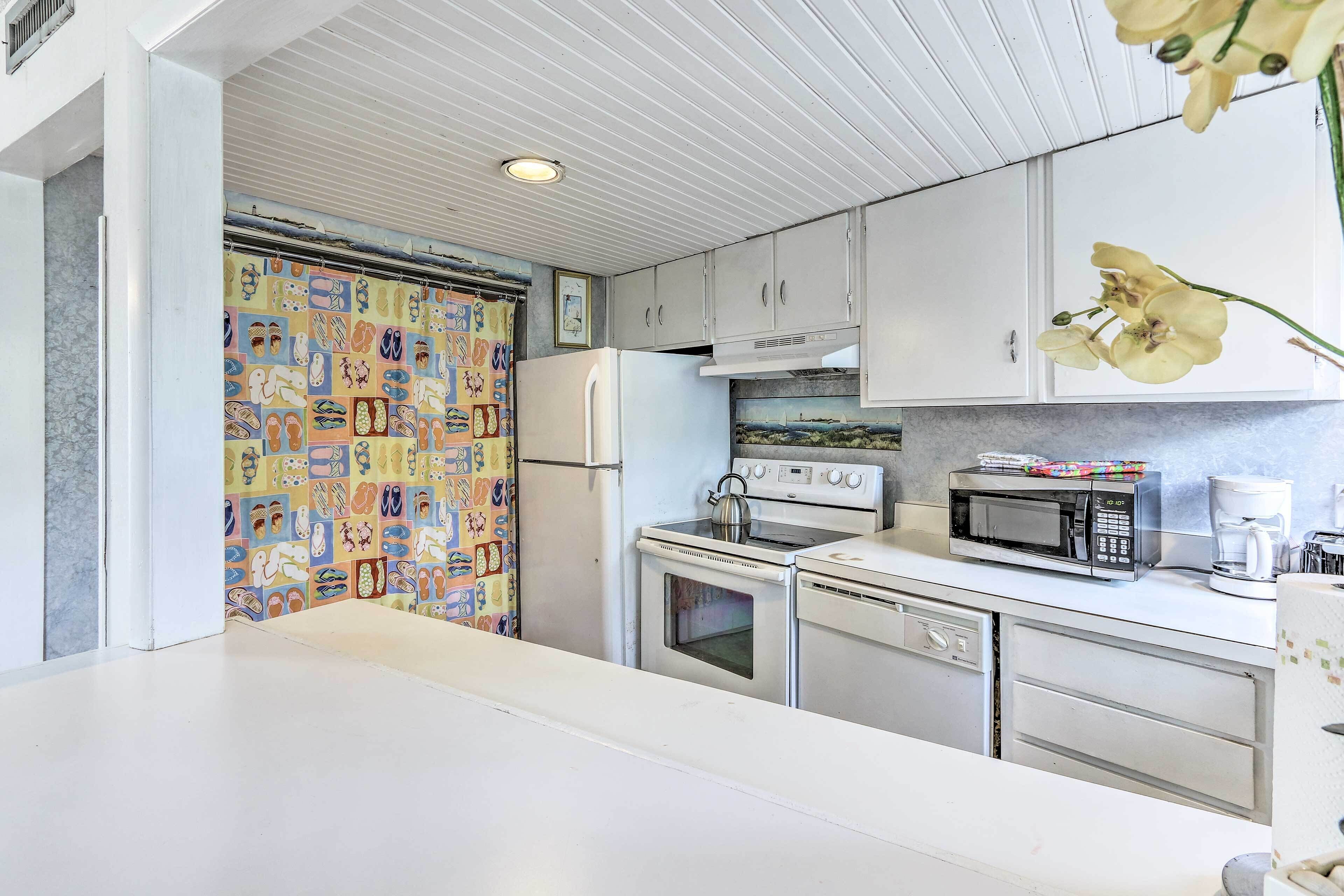 A kitchen with white cabinets, a microwave, a stove, and a refrigerator.