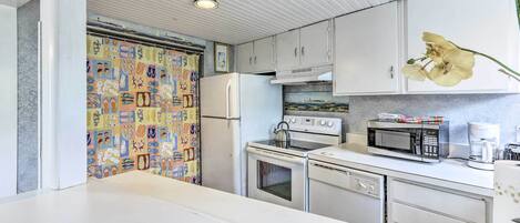 A kitchen with white cabinets, a microwave, a stove, and a refrigerator.