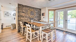 Ein Essbereich mit Holztisch, weißen Stühlen, einer Steinwand und einer großen Uhr.