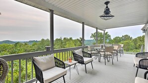 Eine überdachte Terrasse im Freien mit Korbmöbeln und einem Tisch, mit Blick auf eine üppige Landschaft.