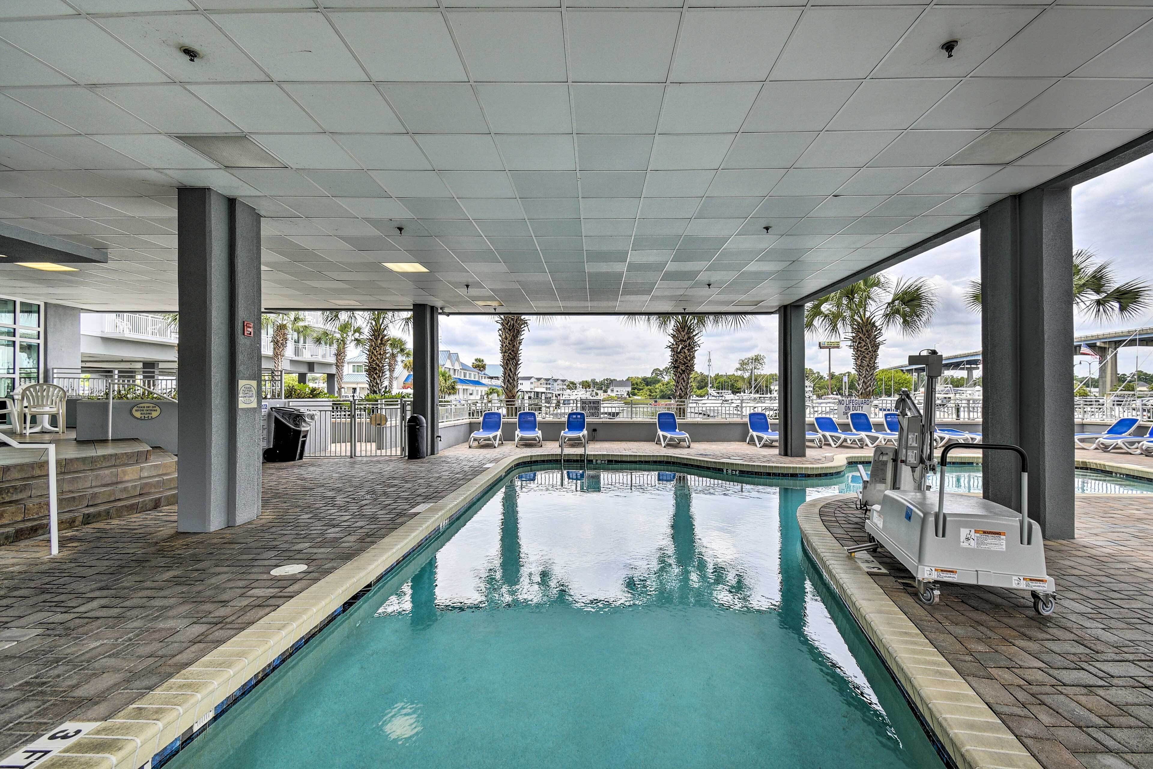 A pool area with a clear view of the pool, blue lounge chairs, and a pool maintenance cart.