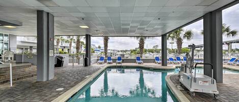 A pool area with a clear view of the pool, blue lounge chairs, and a pool maintenance cart.