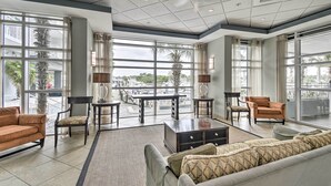 A spacious living area with large windows, a sofa, chairs, and a coffee table. - 2 Mi to Ocean: Waterfront Resort Condo in Nmb! (North Myrtle Beach)