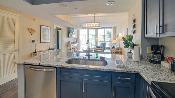 A modern kitchen with dark blue cabinets, a granite countertop, and a stainless steel sink. - 2 Mi to Ocean: Waterfront Resort Condo in Nmb! (North Myrtle Beach)
