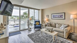 A modern living room with a sofa, armchair, coffee table, and a TV mounted on the wall. - 2 Mi to Ocean: Waterfront Resort Condo in Nmb! (North Myrtle Beach)