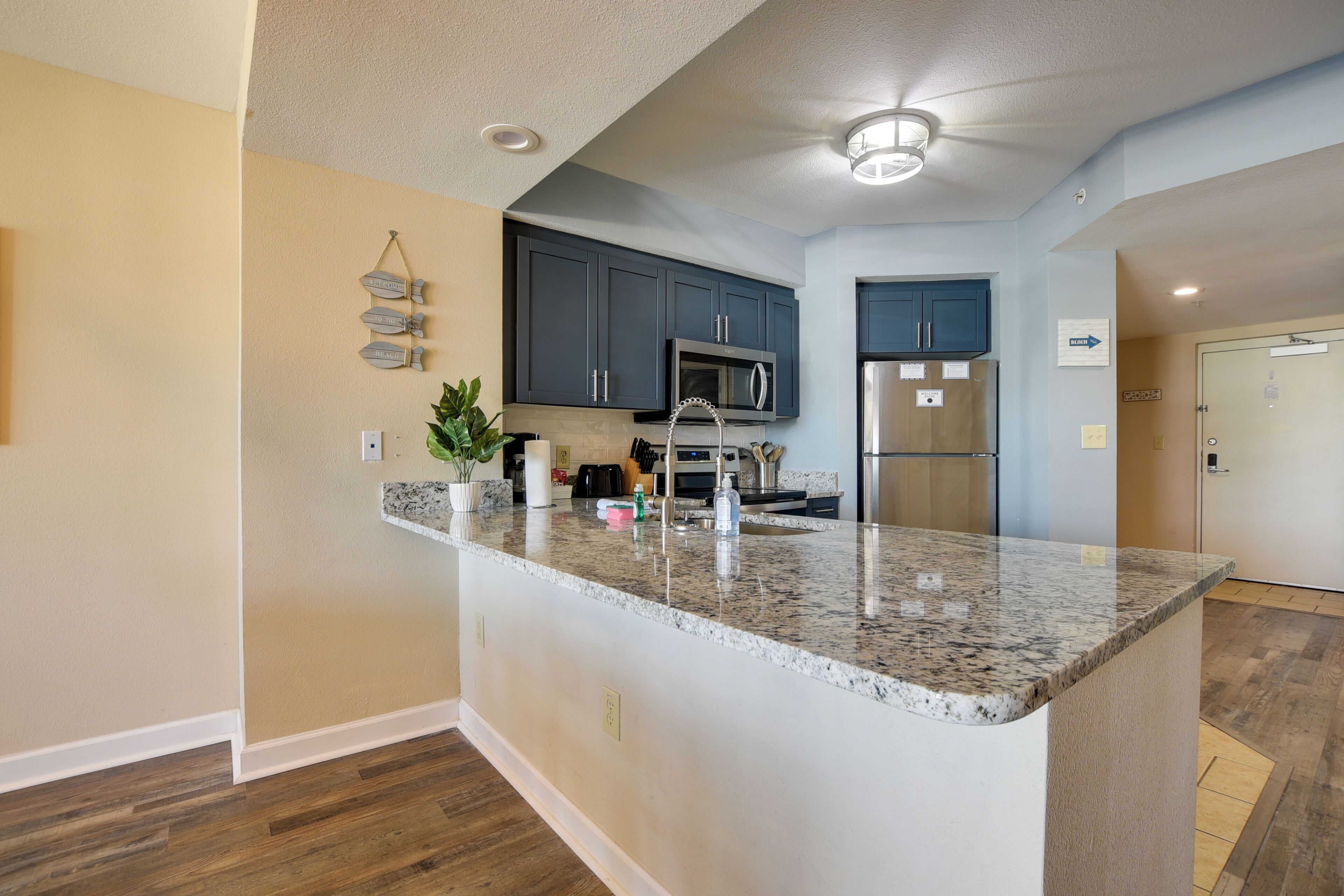 A modern kitchen with dark cabinets, a granite countertop, and stainless steel appliances.