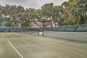 An outdoor tennis court with a net, benches, and trees in the background. - Fiddlers Cove Retreat: Walk to Folly Beach (Hilton Head Island)
