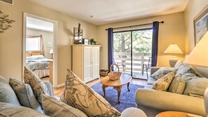 A spacious living room with a large sofa, a coffee table, and a view through a sliding glass door to an outdoor patio. - Walk to Folly Field Beach: Hilton Head Condo (Hilton Head Island)