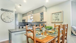 A dining area with a wooden table set for four, surrounded by wooden chairs. A kitchen is visible in the background with a microwave and cabinets. - Holiday Hills Resort Condo: 3 Mi to Branson Strip! (Branson)