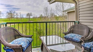 A balcony with wicker chairs and a glass table, overlooking a green field and trees. - Holiday Hills Resort Condo: 3 Mi to Branson Strip! (Branson)