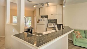 A kitchen with white cabinets, a granite countertop, a microwave, and a refrigerator. - Walk to Beach: HHI Townhome w/ Pool Access! (Hilton Head Island)