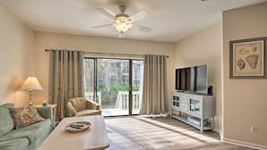 A spacious living room with a ceiling fan, a sofa, a coffee table, and a TV on a stand. - Walk to Beach: HHI Townhome w/ Pool Access! (Hilton Head Island)