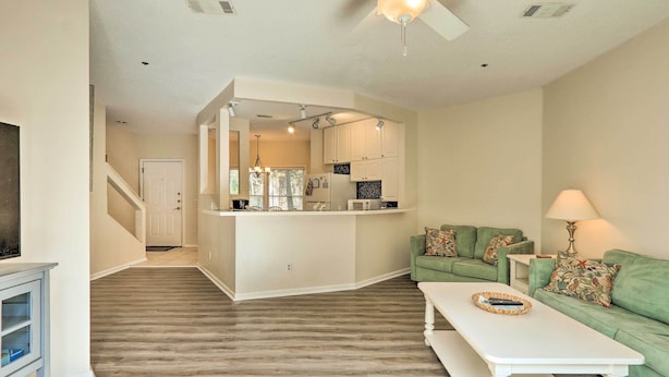 A spacious living area with a green sofa, white coffee table, and a kitchen in the background. - Walk to Beach: HHI Townhome w/ Pool Access! (Hilton Head Island)