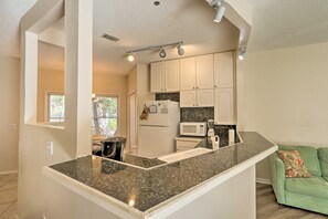 A kitchen with white cabinets, a granite countertop, a microwave, and a refrigerator. - Walk to Beach: HHI Townhome w/ Pool Access! (Hilton Head Island)