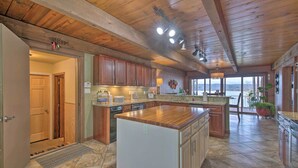 A spacious kitchen with wooden cabinets, a large island, and a view of the outdoors. - Inviting Home w/ Pool & Hot Tub on Table Rock Lake (Lampe)