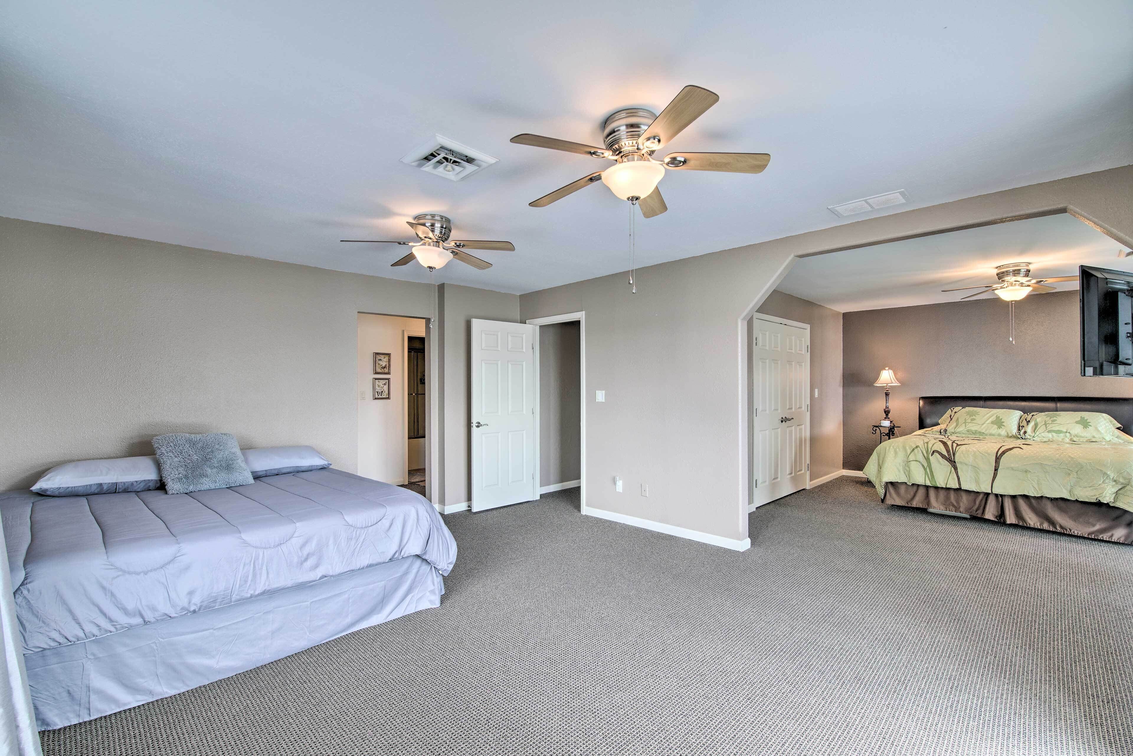 A bedroom with two beds, a ceiling fan, and a carpeted floor.