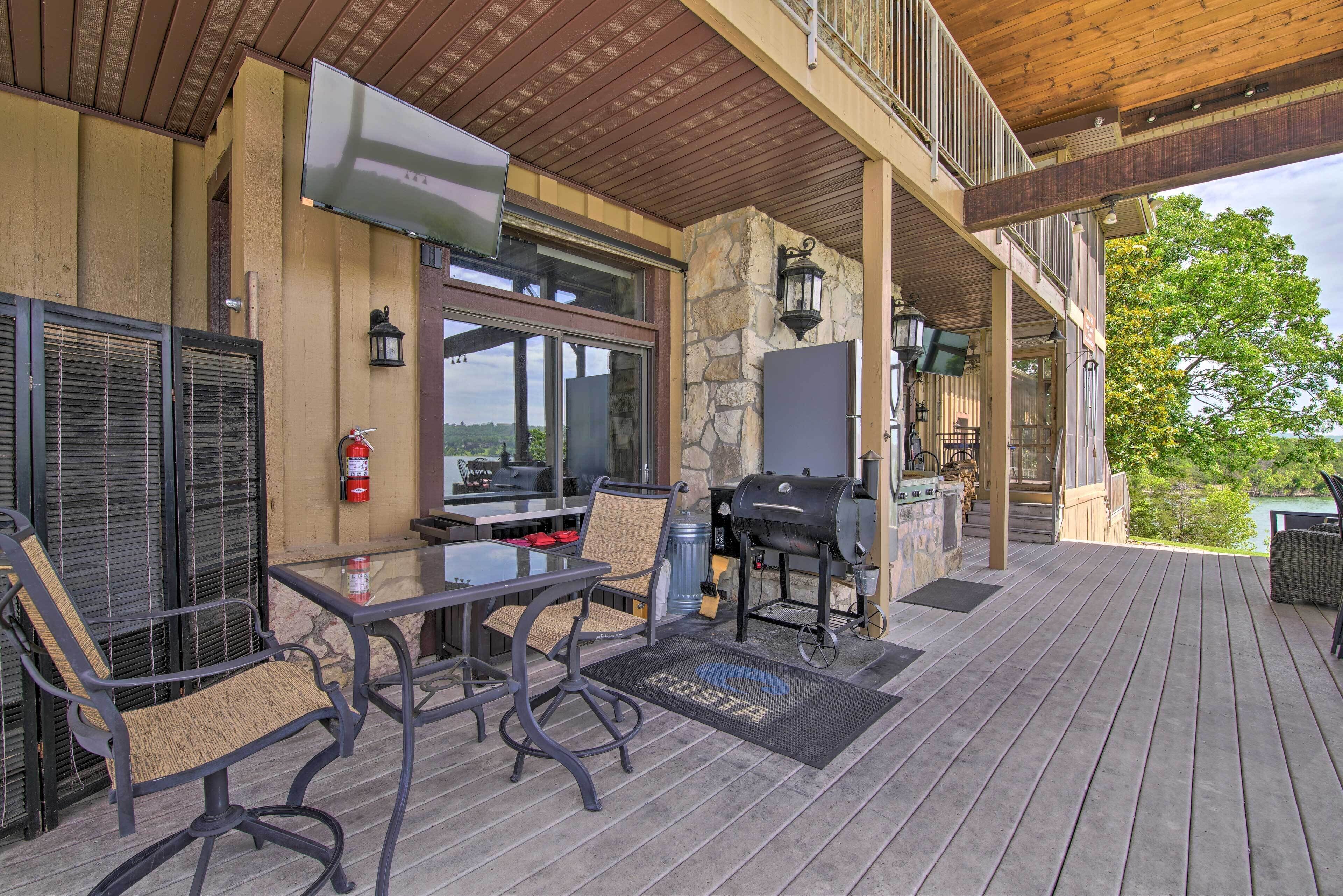 Une terrasse extérieure avec un mur en pierre, un barbecue, une table avec des chaises et un extincteur.