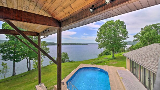 A swimming pool with a wooden deck and a view of a lake. - Inviting Home w/ Pool & Hot Tub on Table Rock Lake (Lampe)