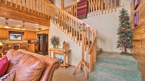 A wooden staircase with a red and white striped runner, a leather sofa, a small table with a vase, and a Christmas tree. - Idyllic Table Rock Lake Cabin w/ Fire Pit! (Golden)