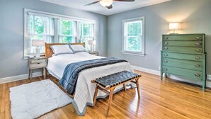 Ein Schlafzimmer mit einem Bett, einer Holzbank, einem Schminktisch und einem Deckenventilator.