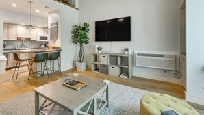 A modern living space with a kitchen, dining area, and a flat-screen TV mounted on the wall. - Pool Access: Idyllic Sea Pines Gem, Walk to Beach (Hilton Head Island)