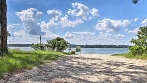 A sandy beach with a sign, trees, and a lake in the background. - Pool Access: Idyllic Sea Pines Gem, Walk to Beach (Hilton Head Island)