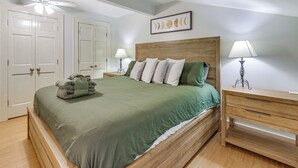A neatly made bed with a green bedspread and pillows, a wooden headboard, a bedside table with a lamp, and a ceiling fan. - Pool Access: Idyllic Sea Pines Gem, Walk to Beach (Hilton Head Island)