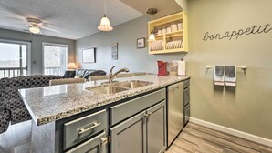 Une cuisine moderne dotée de plans de travail en granit, d’un évier encastré et d’un ventilateur de plafond.