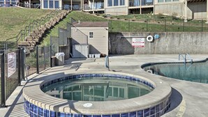 A swimming pool with a tiled edge, a lifeguard stand, and a staircase leading to a building. - Pool + Fishing Docks: Couple's Lake Ozark Condo (Lake Ozark)