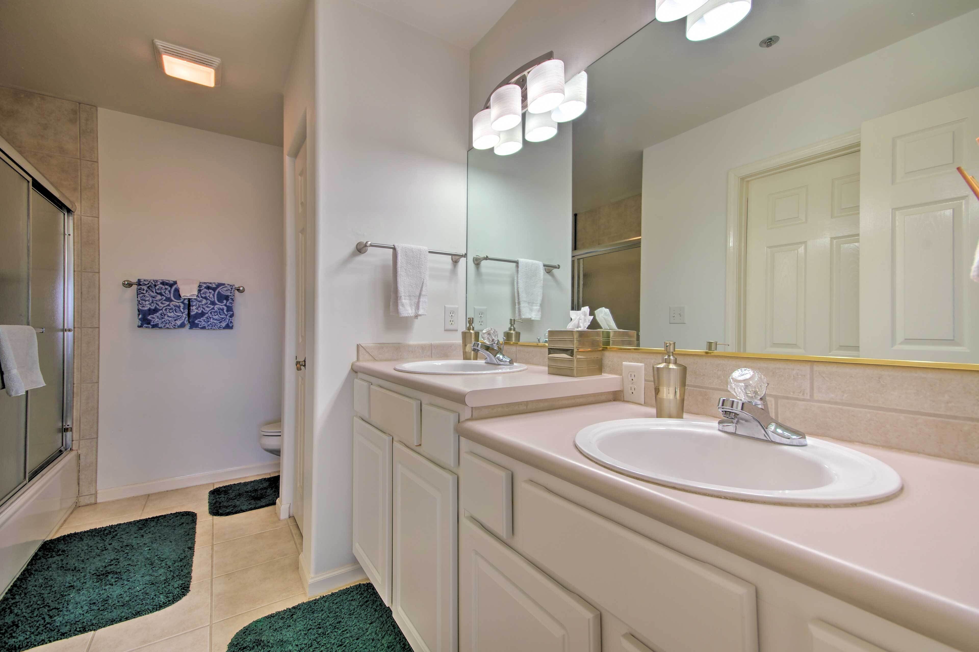 A modern bathroom with two sinks, a large mirror, and a shower area.