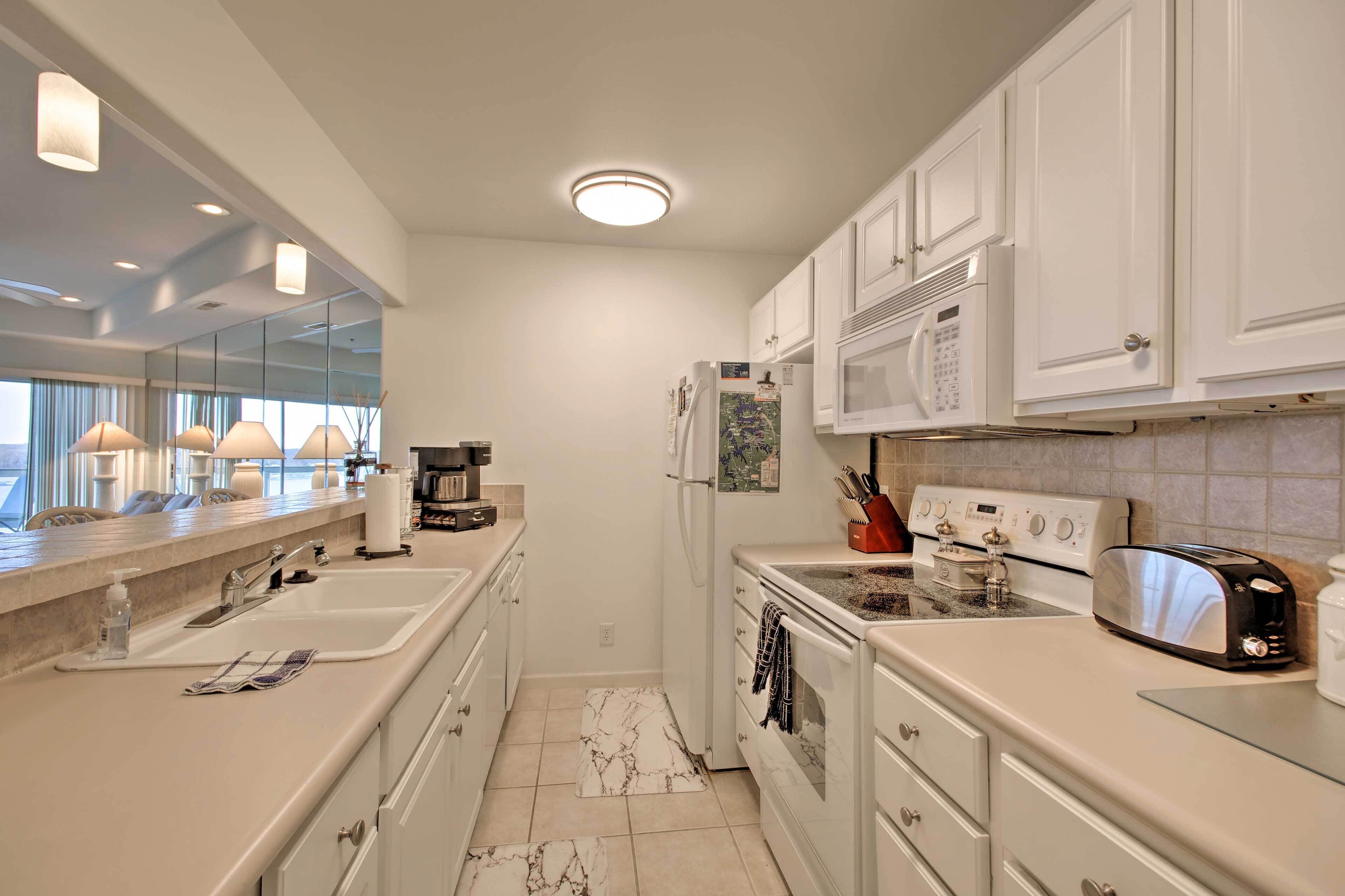 A modern kitchen with white cabinets, a double sink, a microwave, a stove, and a toaster.