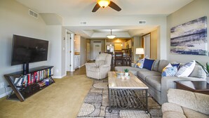 Un salon équipé d’un téléviseur à écran plat, d’un ventilateur de plafond, d’une table basse et d’un canapé.
